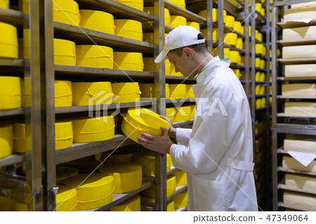 man in a white robe with a head of cheese in his hands is in a cheese warehouse man in a white robe with a head of cheese in his hands is in a cheese warehouse 47349064