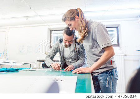 Woman preparing sticker with text to be printed on a T-Shirt Woman preparing sticker with text to be printed on a T-Shirt 47350834