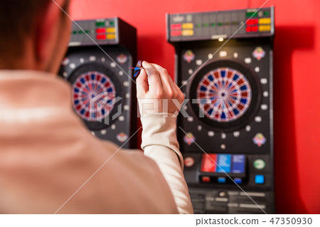 Man aiming at dartboard 47350930