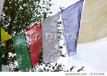 Tibetan flags with mantras hang in a row on a rope Tibetan flags with mantras hang in a row on a rope 47352948