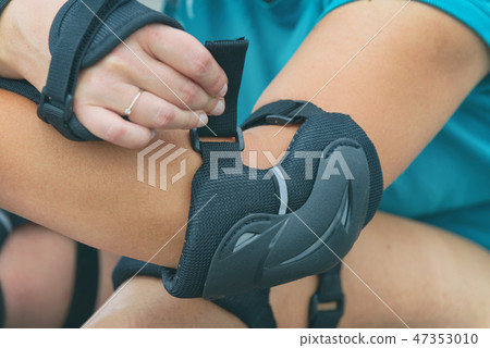 rollerskater putting on protector pads on her leg 47353010