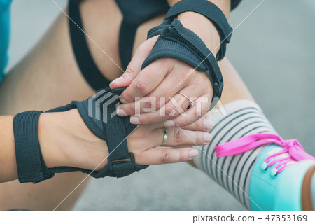 rollerskater putting on protector pads on her leg rollerskater putting on protector pads on her leg 47353169