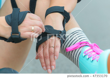 rollerskater putting on protector pads on her leg rollerskater putting on protector pads on her leg 47353170