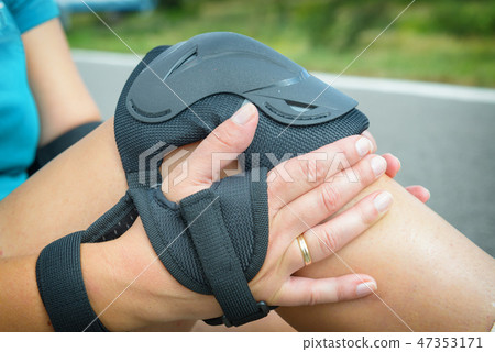 rollerskater putting on protector pads on her leg 47353171