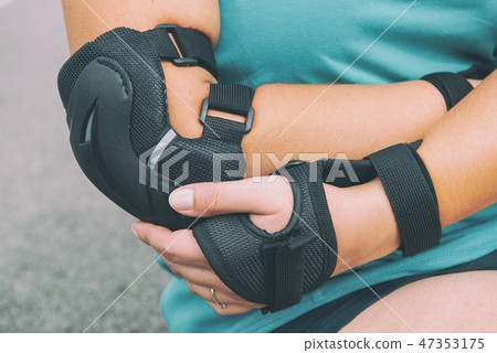 rollerskater putting on protector pads on her leg rollerskater putting on protector pads on her leg 47353175