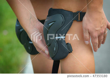 Woman rollerskater putting on knee protector pads 47353180