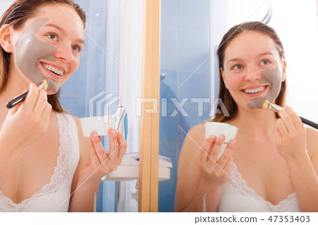 Woman applying mud facial mask 47353403