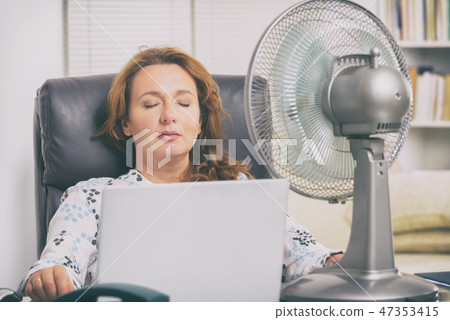 Woman suffers from heat in the office or at home Woman suffers from heat in the office or at home 47353415