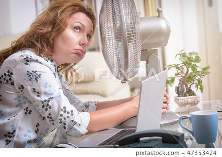 Woman suffers from heat in the office or at home 47353424