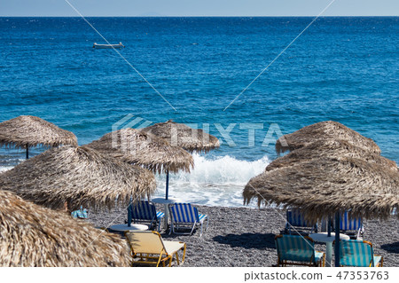 beach with umbrellas and deck chairs in Santorini 47353763