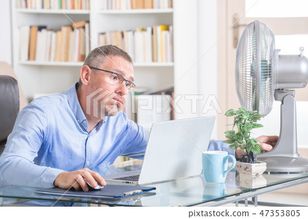 Man suffers from heat in the office or at home Man suffers from heat in the office or at home 47353805