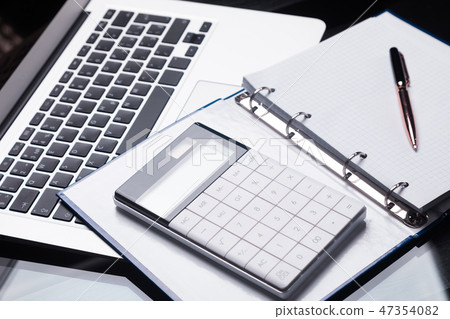 Modern calculator is on a laptop and on an open notebook Modern calculator is on a laptop and on an open notebook 47354082