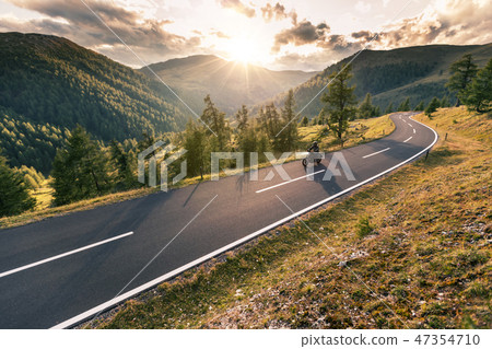 Motorcycle driver riding in Alpine road Motorcycle driver riding in Alpine road 47354710