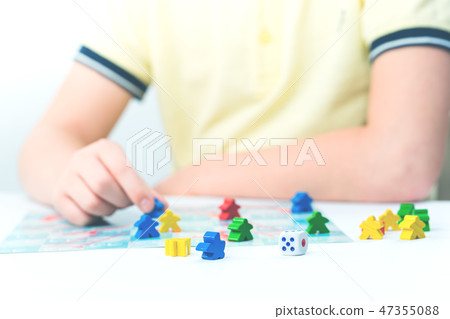 Child plays a board game on table 47355088