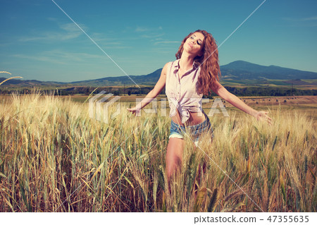 Young, beautiful woman in a wheat field. Tuscany, Italy Young, beautiful woman in a wheat field. Tuscany, Italy 47355635
