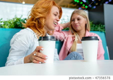 Two beautiful female friend sit in a cafe after their purchases during sales Two beautiful female friend sit in a cafe after their purchases during sales 47356578