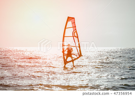 Surfer riding waves in a beautiful sunny day. Young man enjoying the wind and the ocean surfing. 47356954
