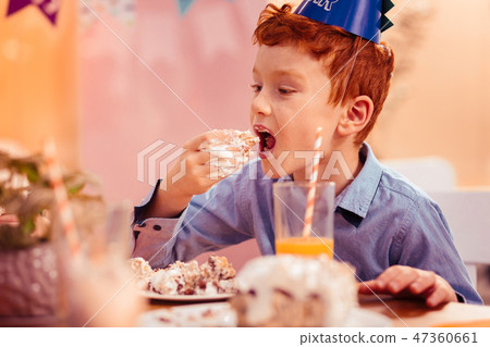 Hungry red-haired boy eating tasty birthday cake Hungry red-haired boy eating tasty birthday cake 47360661