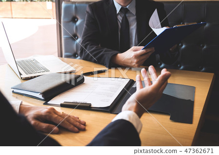 Employer or recruiter holding reading a resume during about his Employer or recruiter holding reading a resume during about his 47362671