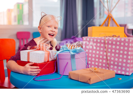 Happy blonde girl sitting at the table with presents Happy blonde girl sitting at the table with presents 47363690