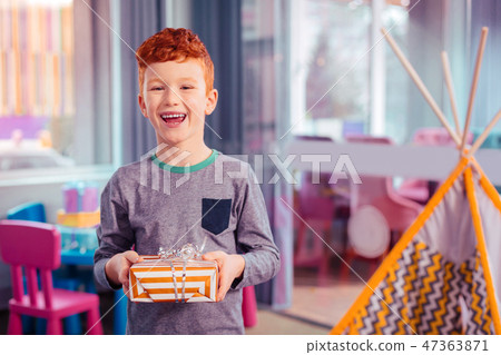 Delighted Red Haired Kid Keeping Smile On His Face Stock Photo
