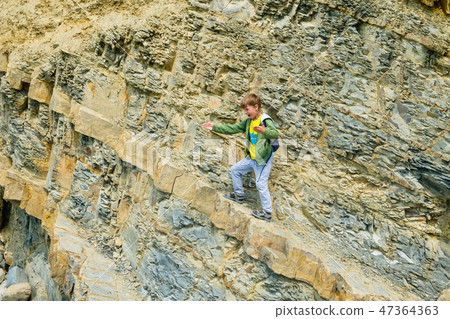 Six-year-old boy on a rock climbing with a backpack. 47364363