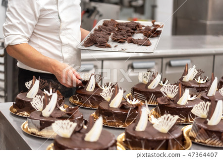 Pastry Chef decorating chocolate cakes in the kitchen of pastry shop 47364407