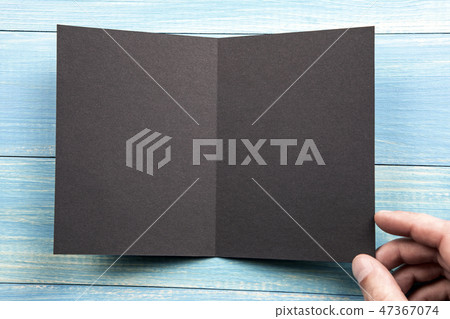 Mens hand holding black booklet 47367074