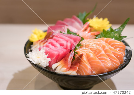 Mixed sliced fish sashimi on ice in black bowl 47370242