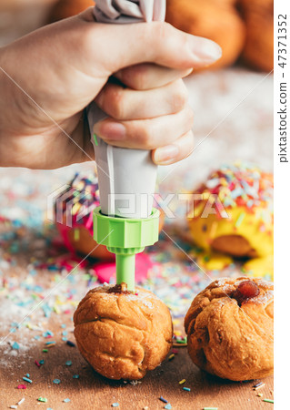 Woman filling homemade doughnut with red jam 47371352
