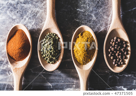 Four wooden kitchen spoons with different spices 47371505