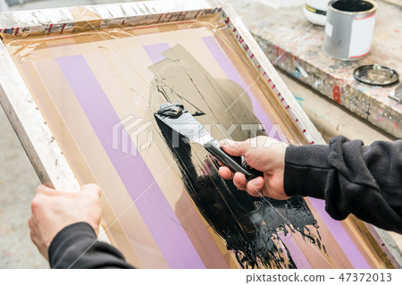 Man squeegeeing silkscreen in a workshop. Serigraphy Man squeegeeing silkscreen in a workshop. Serigraphy 47372013