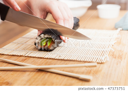 Preparing sushi, cutting. Salmon, avocado, rice and chopsticks on wooden table. 47373751