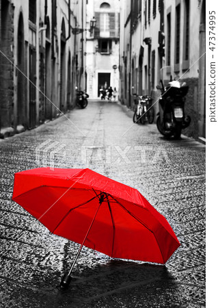 Red umbrella on cobblestone street in the old town. Wind and rain Red umbrella on cobblestone street in the old town. Wind and rain 47374995
