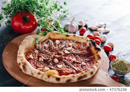Pizza with anchois and garlic on wooden board. 47376286