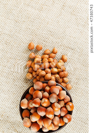 Peeled hazelnuts in a wooden, dark brown cup on  47380743