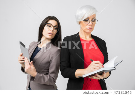 Portrait of two young girls with a tablet and a diary in their hands isolated on a light background 47381845