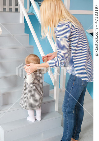 Young beautiful happy mother help her daughter doing her first step 47383197