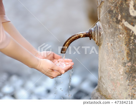 Closeup photo of woman washing hands in fountain. 47384218