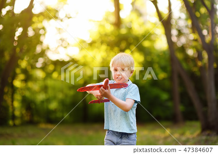 Boy playing with toy airplane in the sunny park. Boy playing with toy airplane in the sunny park. 47384607