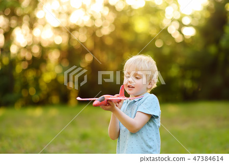 Boy playing with toy airplane in the sunny park. Boy playing with toy airplane in the sunny park. 47384614