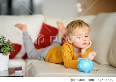 Boy looks on moneybox, plans of what he can buy. 47385249