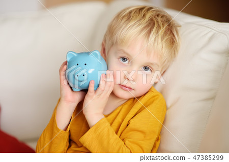 Little boy shaking a piggy moneybox and dreams  47385299