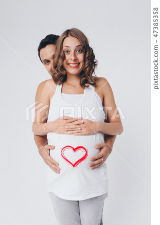 Romantic pregnancy. man hugging pregnant wife on white background. heart on the belly. Valentine day Romantic pregnancy. man hugging pregnant wife on white background. heart on the belly. Valentine day 47385358