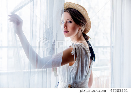 Woman in white dress holding lavender near window 47385361
