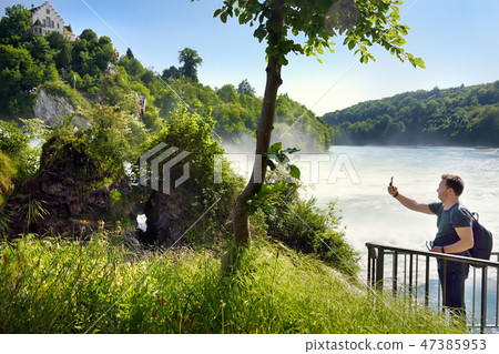 Man taking a photo of Rhine falls, Switzerland 47385953