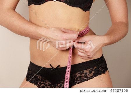 Woman measuring her waist closeup Woman measuring her waist closeup 47387106