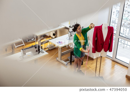 Pretty asian dressmaker with bright bracelets checking the size 47394050