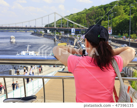 Young woman looks the embankment bridge and river Young woman looks the embankment bridge and river 47396135