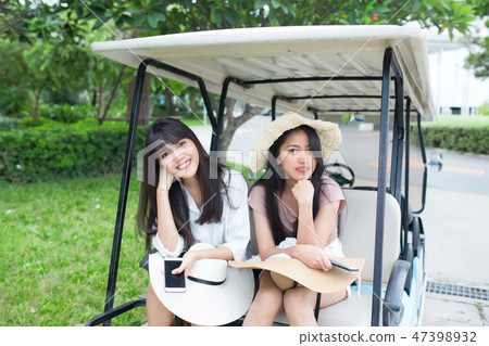 two young asian women sitting on golf cart two young asian women sitting on golf cart 47398932